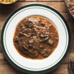 El fricandó es uno de esos guisos catalanes que conquistan con muy poco: ternera finamente laminada, una salsa llena de sabor y perfecto para hacer en cantidad. Se suele servir con patatas fritas, arroz blanco y mucho pan para mojar y no dejar ni una gota. Y lo mejor de todo es que, cuando aprendes a hacerlo, se convierte en una receta comodín: se prepara con antelación, mejora de un día para otro y te soluciona desde una comida familiar hasta una cena especial sin complicaciones. Vamos, una receta tradicional que hoy te cuento cómo hacer para que no falte en tu repertorio. | Receta de Paula's Apron