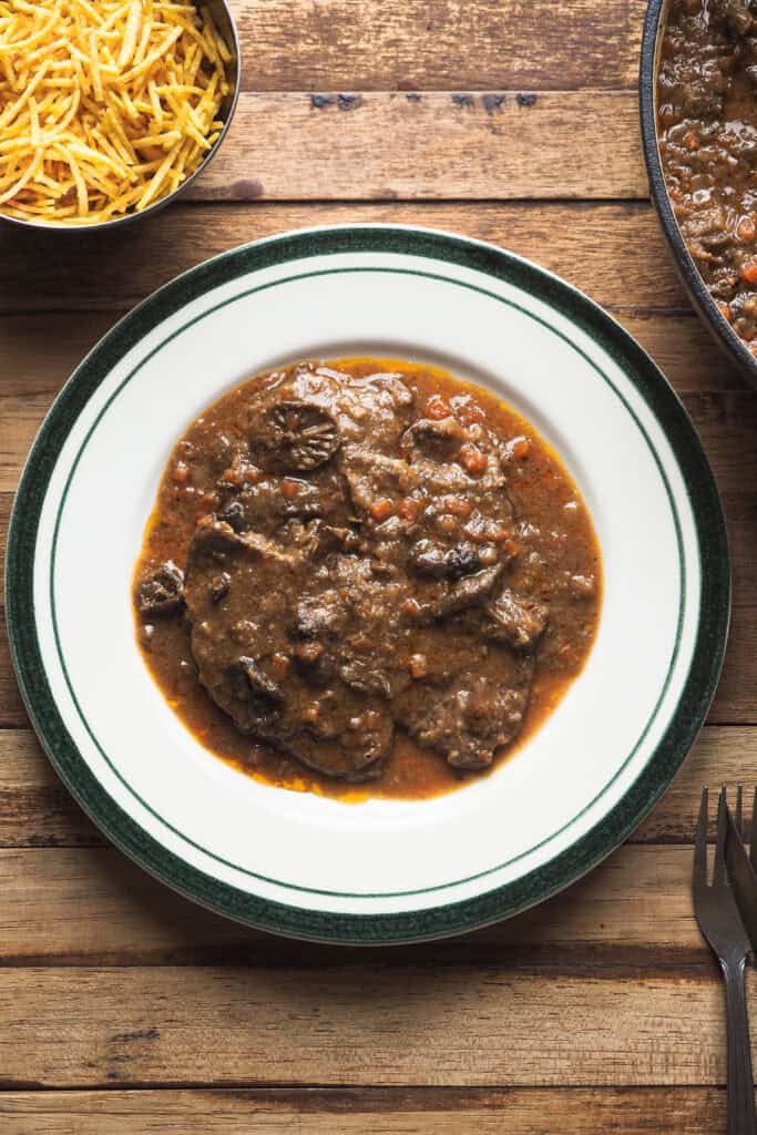 El fricandó es uno de esos guisos catalanes que conquistan con muy poco: ternera finamente laminada, una salsa llena de sabor y perfecto para hacer en cantidad. Se suele servir con patatas fritas, arroz blanco y mucho pan para mojar y no dejar ni una gota. Y lo mejor de todo es que, cuando aprendes a hacerlo, se convierte en una receta comodín: se prepara con antelación, mejora de un día para otro y te soluciona desde una comida familiar hasta una cena especial sin complicaciones. Vamos, una receta tradicional que hoy te cuento cómo hacer para que no falte en tu repertorio. | Receta de Paula's Apron