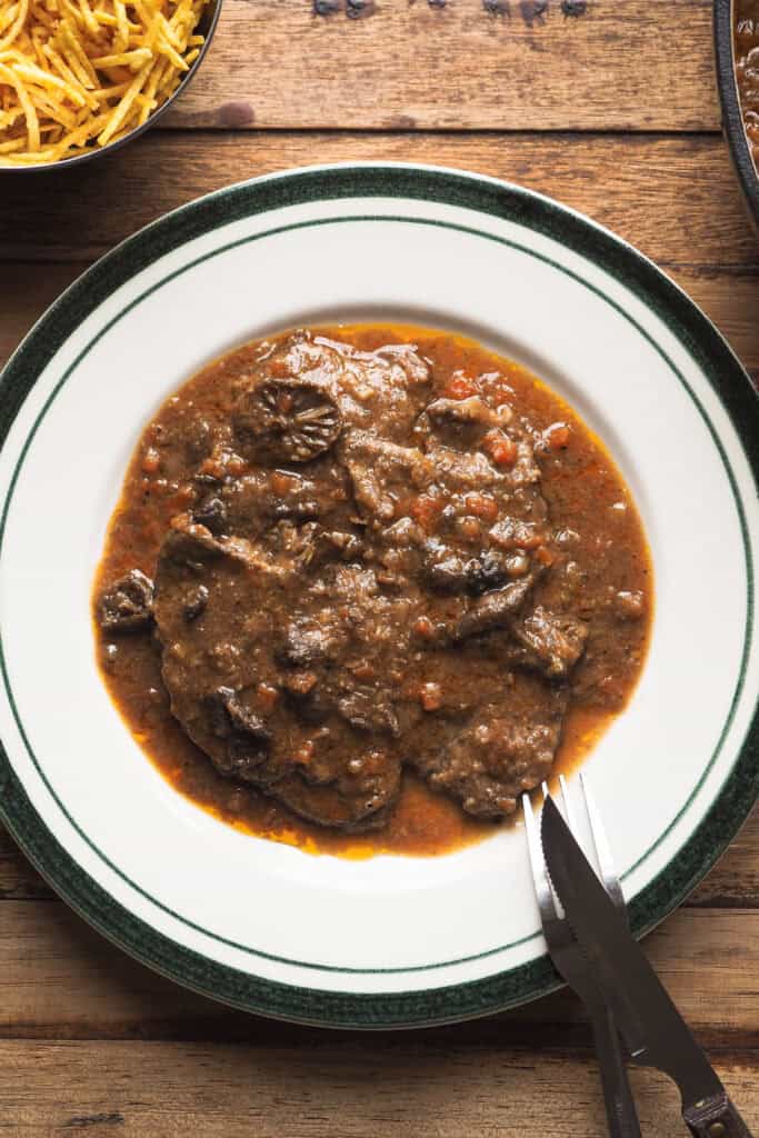 El fricandó es uno de esos guisos catalanes que conquistan con muy poco: ternera finamente laminada, una salsa llena de sabor y perfecto para hacer en cantidad. Se suele servir con patatas fritas, arroz blanco y mucho pan para mojar y no dejar ni una gota. Y lo mejor de todo es que, cuando aprendes a hacerlo, se convierte en una receta comodín: se prepara con antelación, mejora de un día para otro y te soluciona desde una comida familiar hasta una cena especial sin complicaciones. Vamos, una receta tradicional que hoy te cuento cómo hacer para que no falte en tu repertorio. | Receta de Paula's Apron