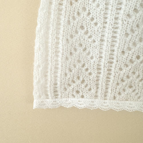 Delicate white lace fabric with intricate patterns and scalloped edges, ideal for sewing, craft projects, or elegant clothing design. Perfect for adding a touch of sophistication and style to any fashion or home decor item.