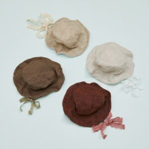 Four linen pet hats in beige, brown, rust, and light cream colors with decorative bows, ideal for stylish pet accessories from Paws With Fashion.
