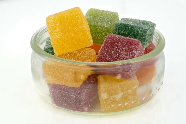 Colorful THC-infused gummies in a clear glass jar, coated with sugar crystals, ideal for relaxation and sleep support.