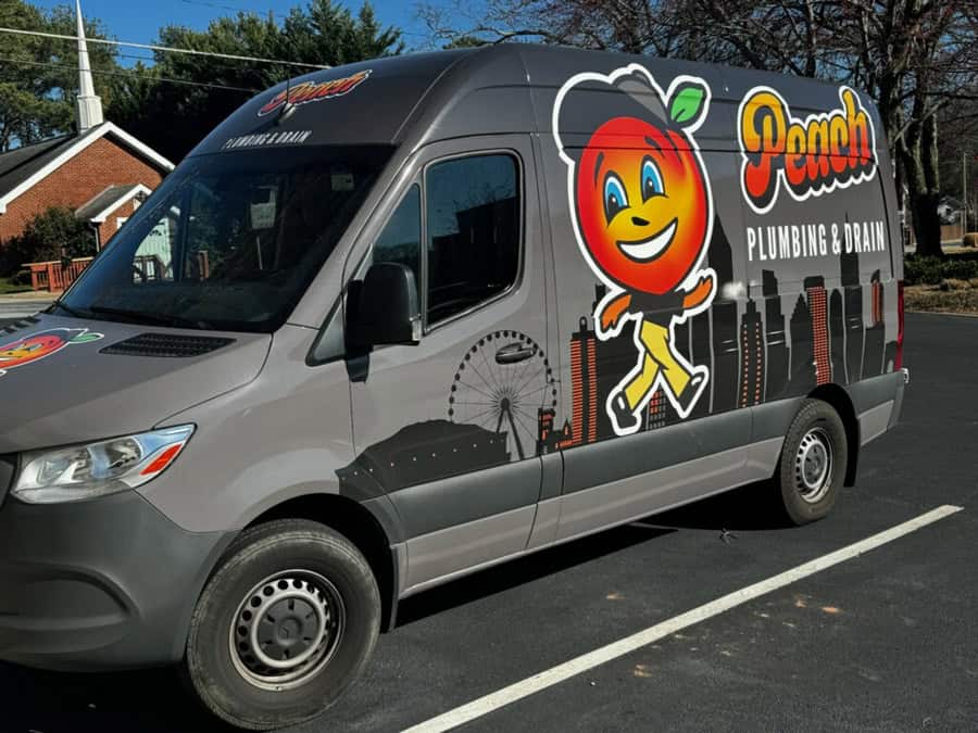 Peach Plumbing & Drain service van featuring the smiling peach mascot and Atlanta skyline graphic, representing trusted local plumbing services in Atlanta.