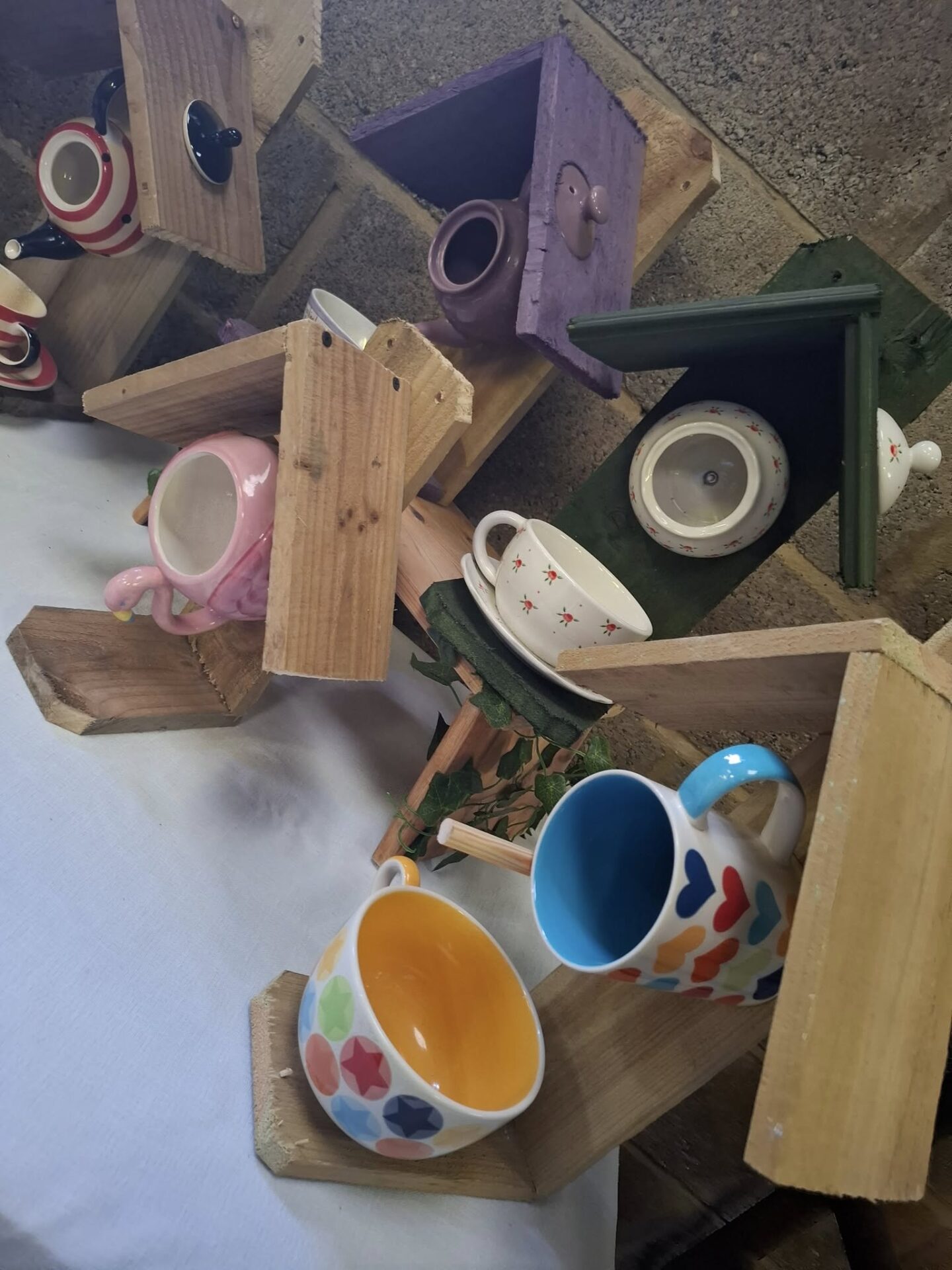 Colourful handmade upcycled bird feeders with wooden and ceramic elements.
