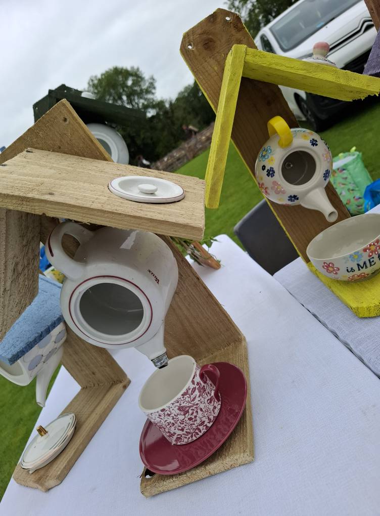 Upcycled wooden bird feeders with colourful teacups and teapots for garden birds.