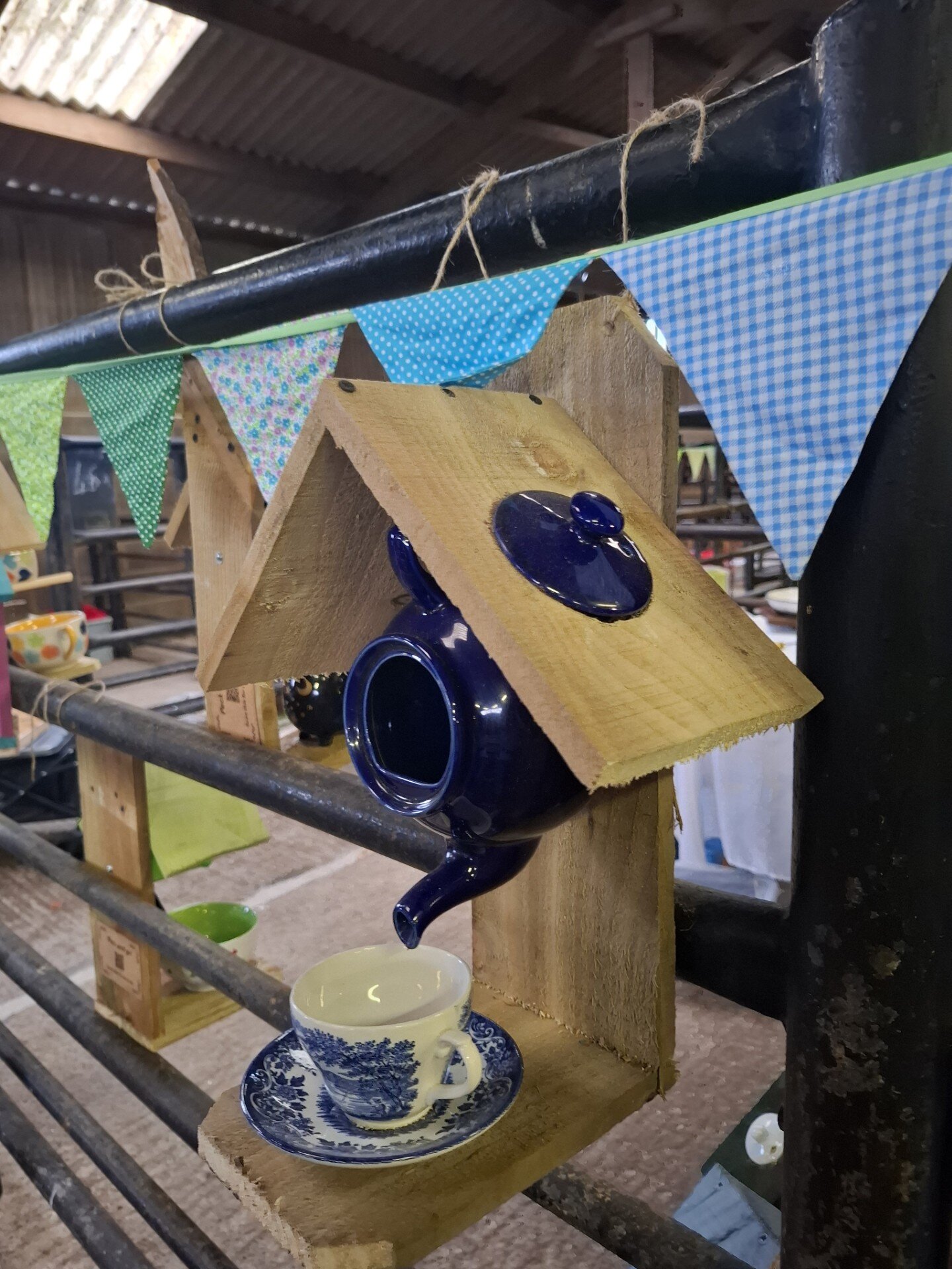 Upcycled wooden bird feeder with ceramic teapot and cup.