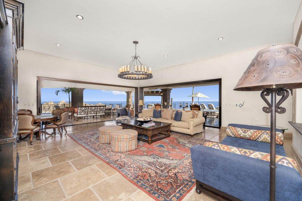 Elegant Pedregal living room with panoramic ocean views, featuring classic furniture, a statement chandelier, and an inviting outdoor terrace for luxurious relaxation and entertaining.