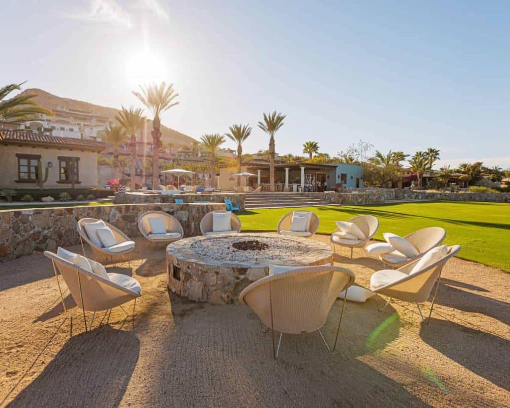 Luxury Pedregal Outdoor Lounge With Fire Pit And Mountain Views, Palm Trees, And Modern Hacienda Style Houses, Perfect For Relaxing And Socializing In A Premier Real Estate Community In Mexico.