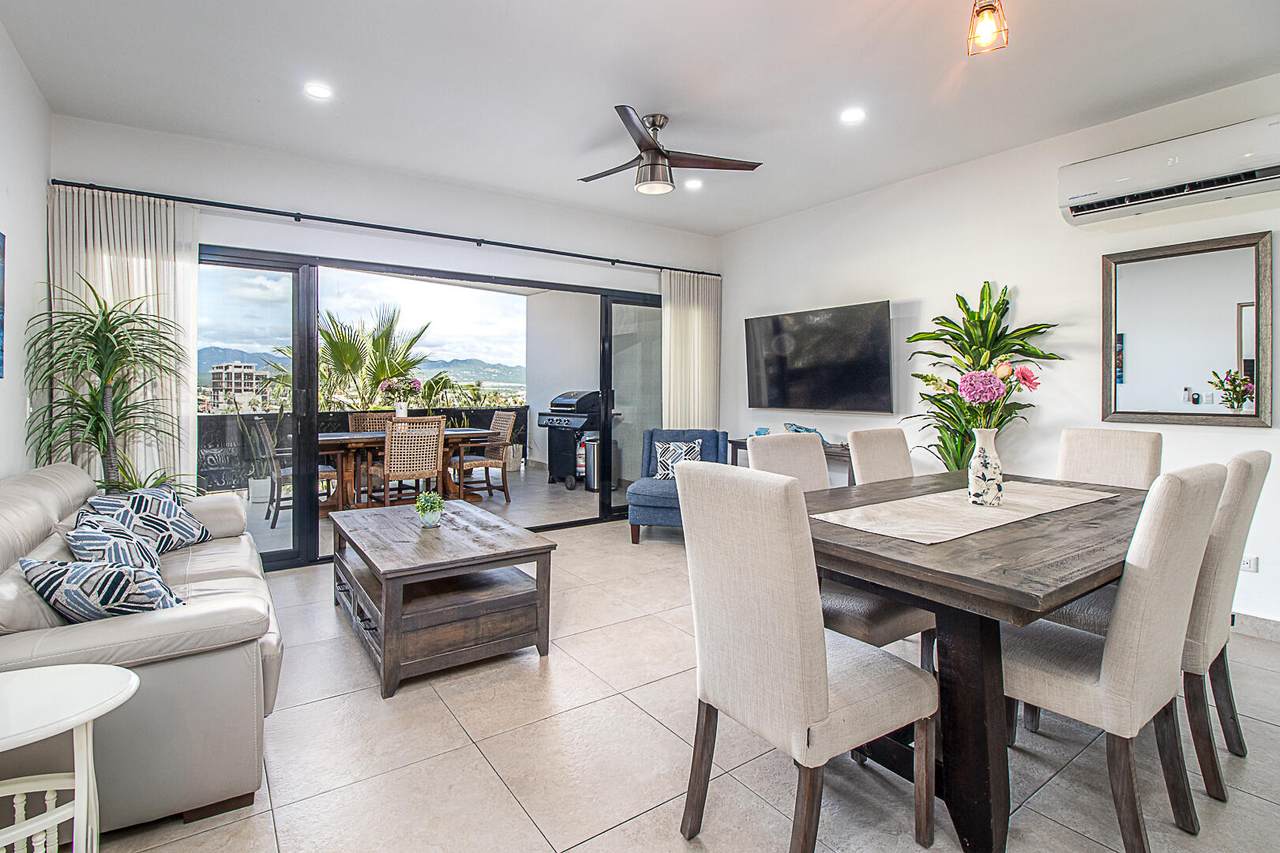 Camino Del Colegio , A03 – Homes For Sale In Pedregal Modern Pedregal Condo Interior With Bright Living And Dining Areas, Large Sliding Doors To Balcony, Stylish Furnishings, And Scenic Mountain Views In The Background.