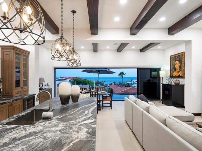 Contemporary Pedregal Living Room With Ocean Views, Featuring A Spacious Open-Concept Design, Elegant Lighting Fixtures, Modern Furniture, And Large Windows That Showcase The Scenic Coastal Landscape.