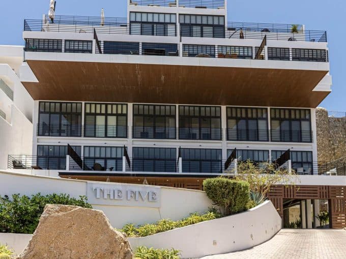 Luxury Modern Pedregal Condo Building With Glass Balconies And Wooden Accents, Located In A Vibrant Upscale Neighborhood, Offering Stunning Ocean Views And Stylish Contemporary Architecture.
