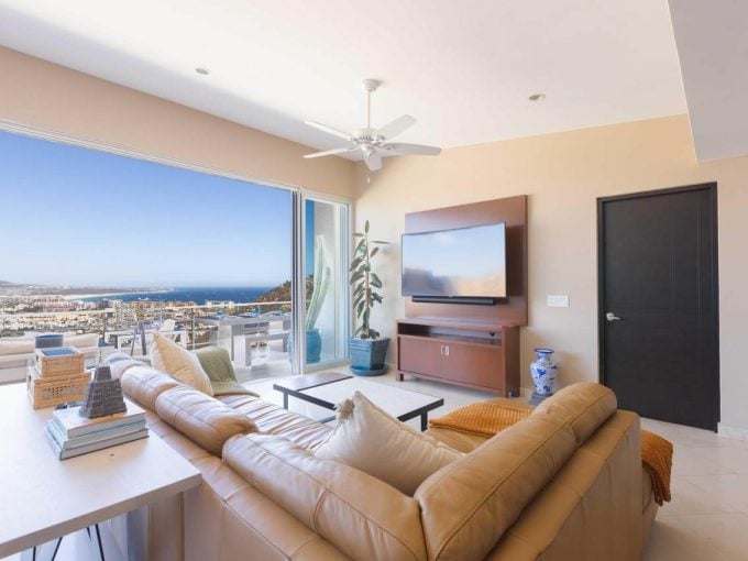 Bright Living Room In Pedregal Luxury Apartment With Expansive Ocean Views Through Large Glass Sliding Doors. Stylish Decor, Modern Furnishings, And Indoor-Outdoor Flow Showcase Pedregal’s Upscale Coastal Lifestyle.