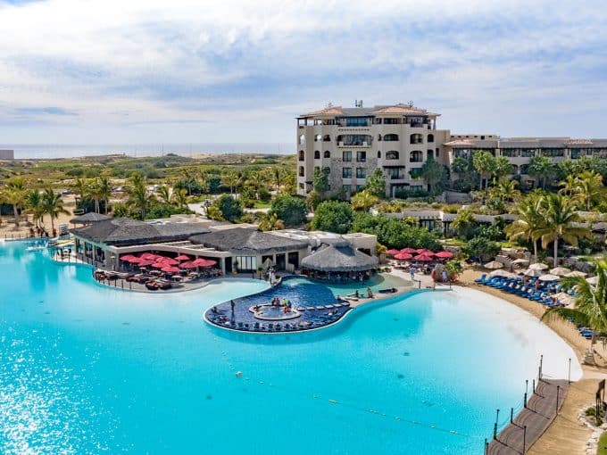 Luxurious Pedregal Resort Pool Area With Palm Trees, Sun Loungers, And Beachfront Views, Ideal For Relaxation And Leisure. Pedregal Offers Exclusive Real Estate Opportunities In A Stunning Coastal Setting.