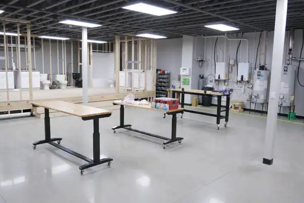 A clean, industrial workspace with rolling tables, exposed ceiling, unfinished walls, and utility equipment along the back wall—ideal for Bloomington Plumbing Repair projects.