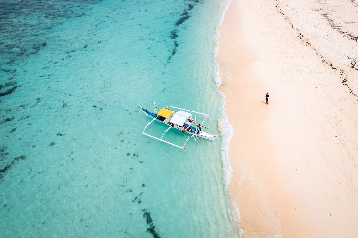 Boat by the shore and a men with blue water