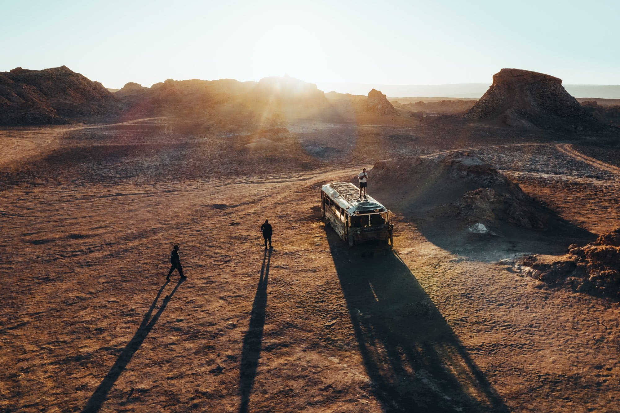 Man standing on top of a van in the desert