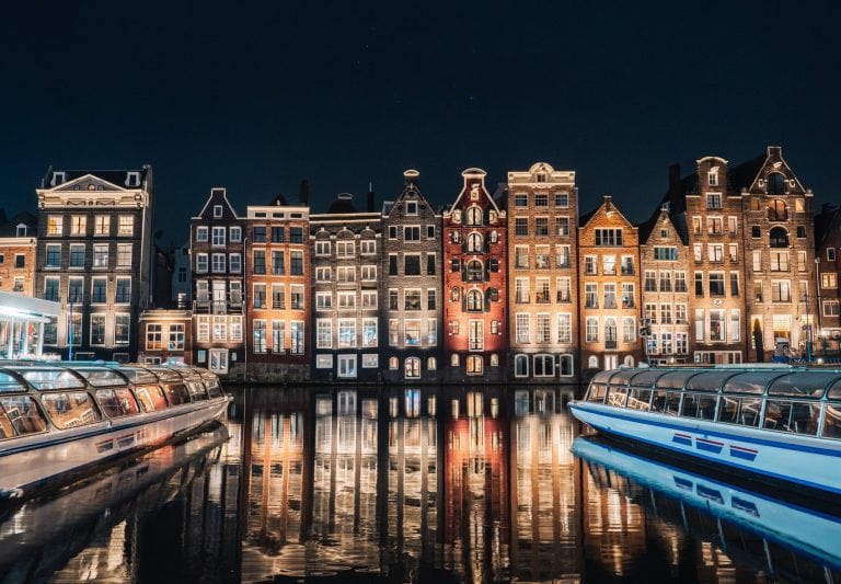 night shot of canal and building in amsterdam