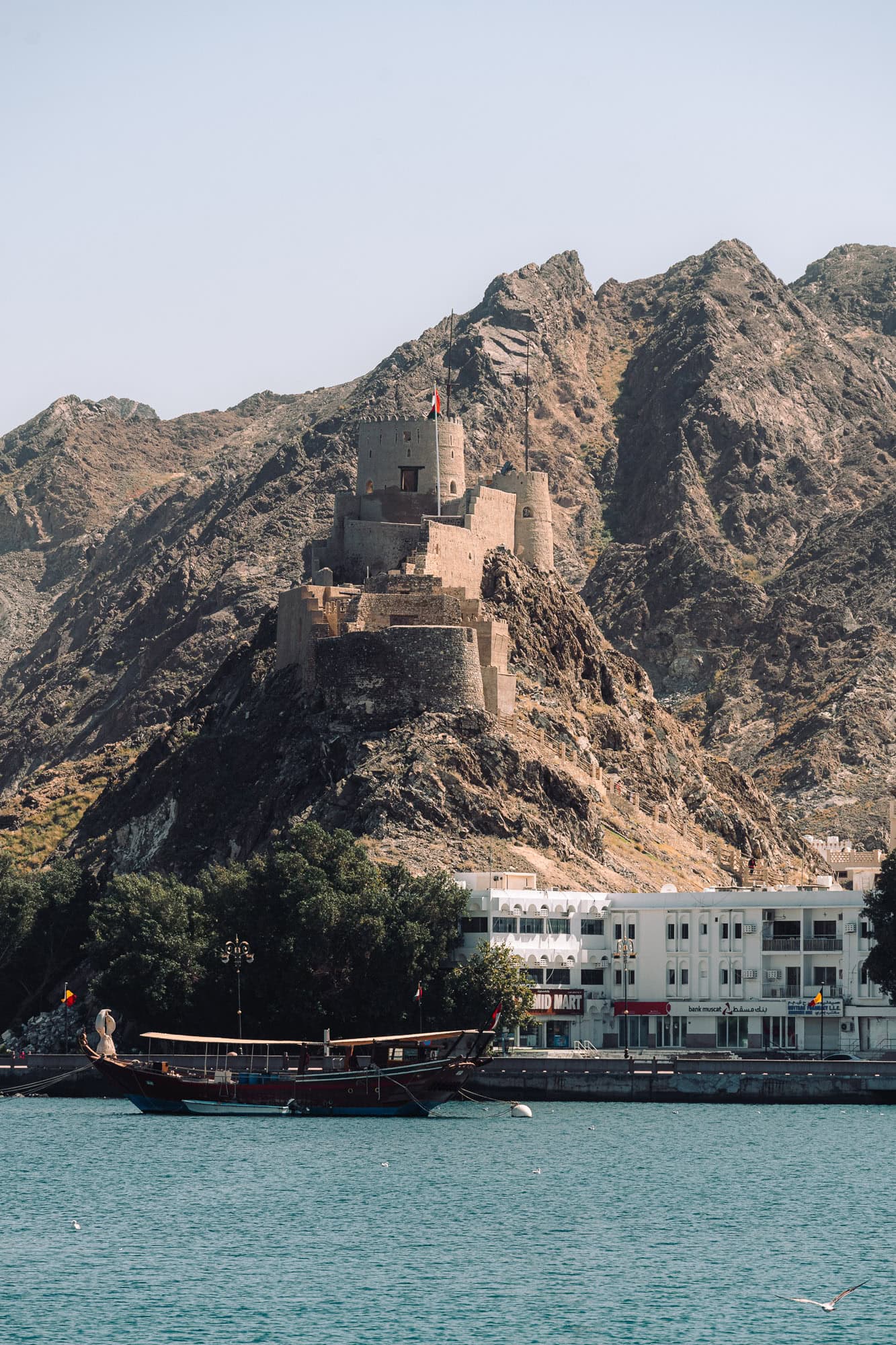 Photo of a fort with mountains in the backdrop in Mutrah, Oman