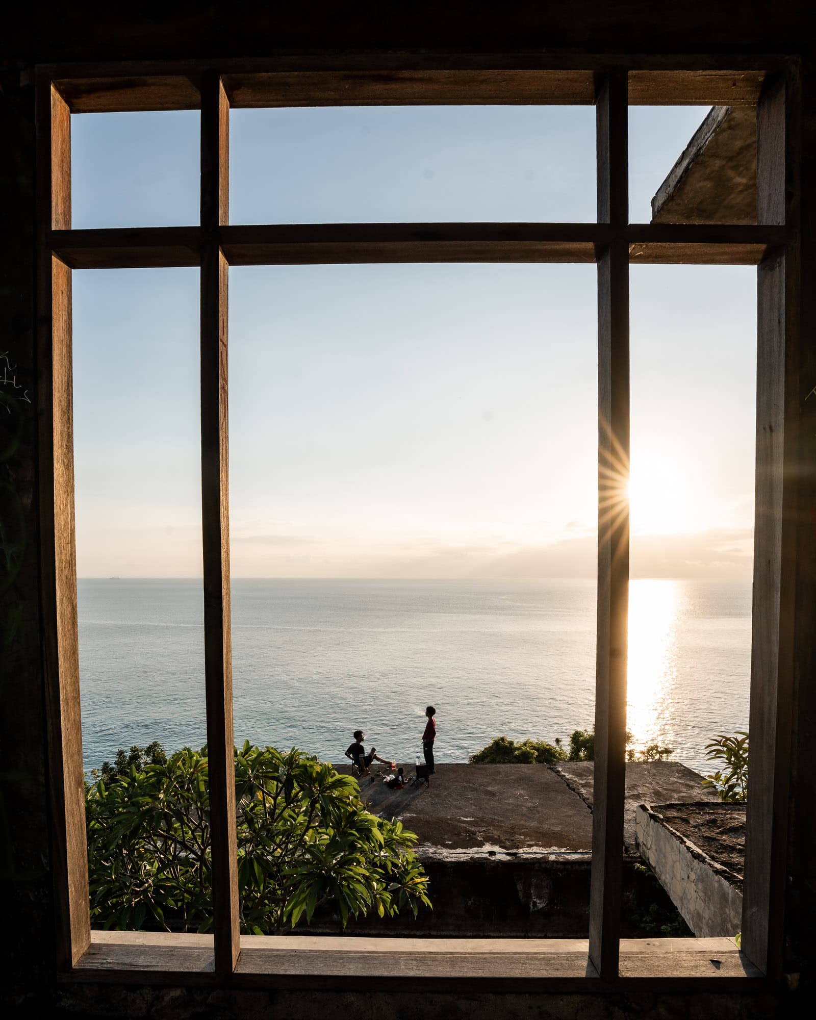 Boys enjoying the sunset in Lombok, taken through a window frame.