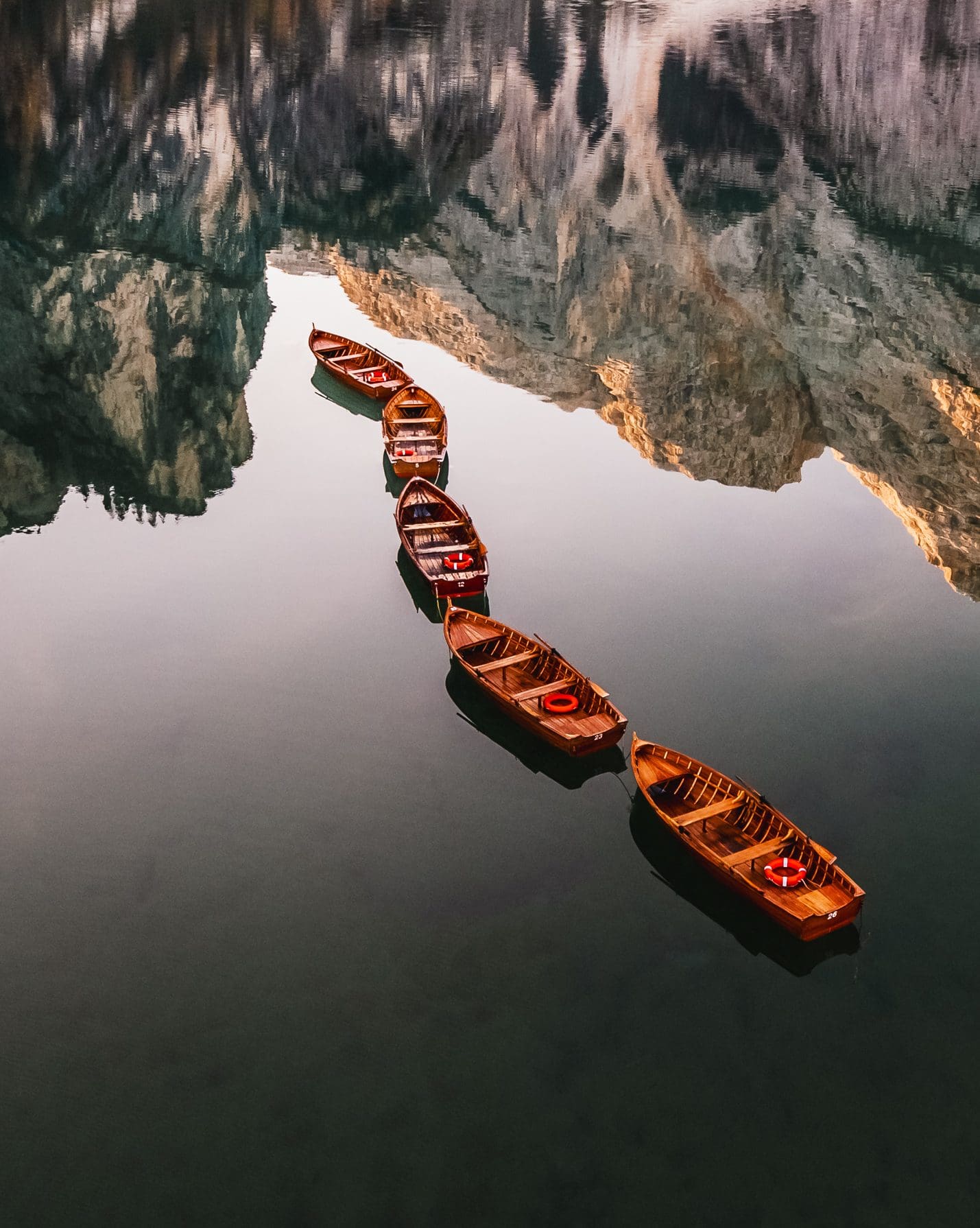Boats in Lago di Braies on a mountain reflection in the italian dolomites