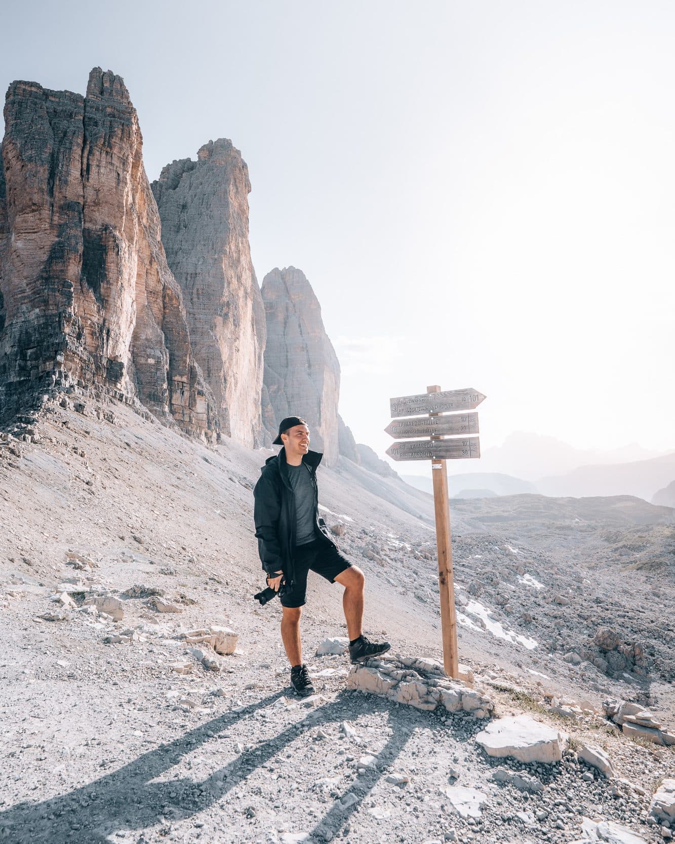 Person standing in front of route sign in Dolomites, with Tre Cime in the background