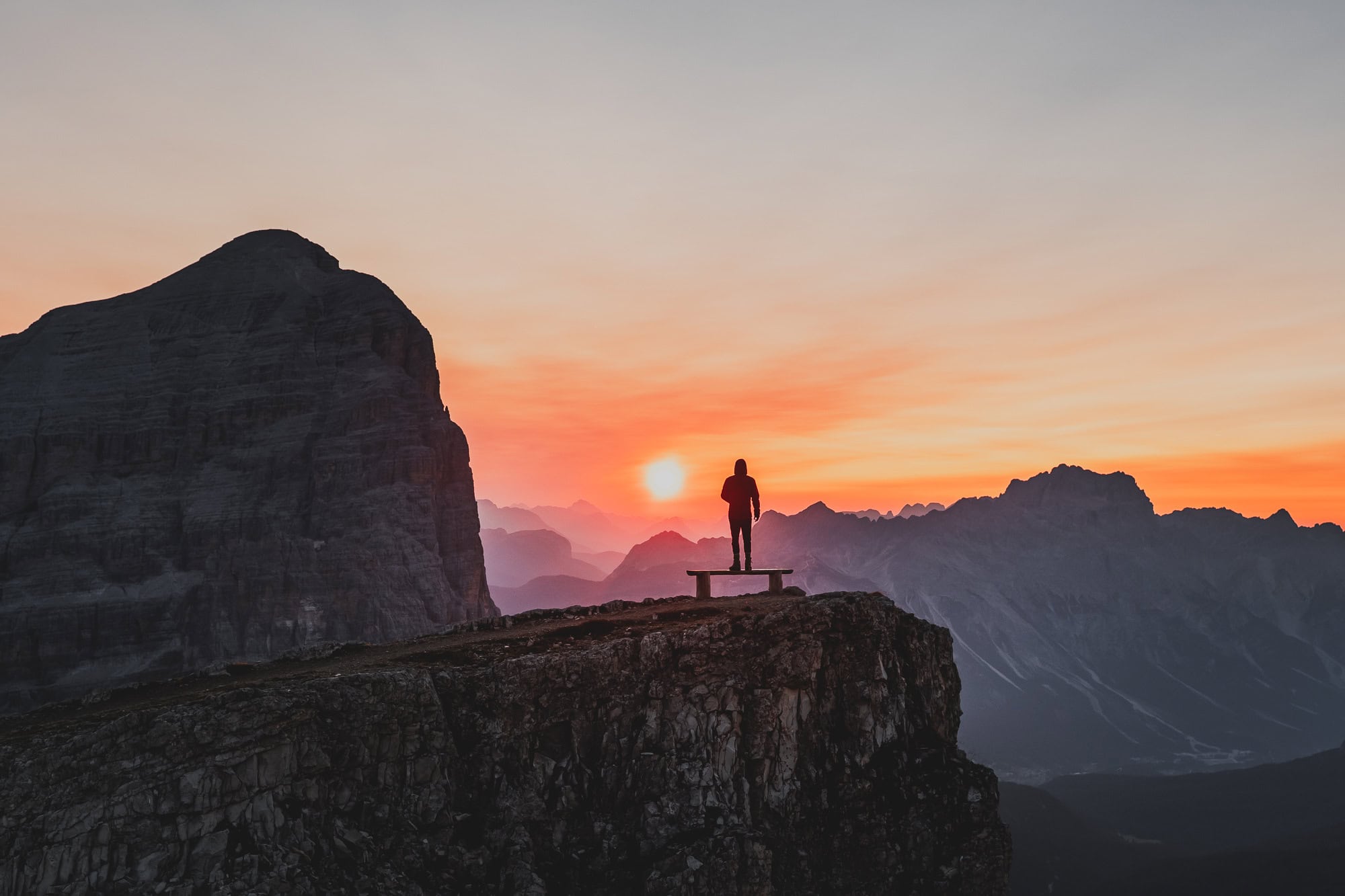Person as silhouette in the mountains while staring at a sunrise