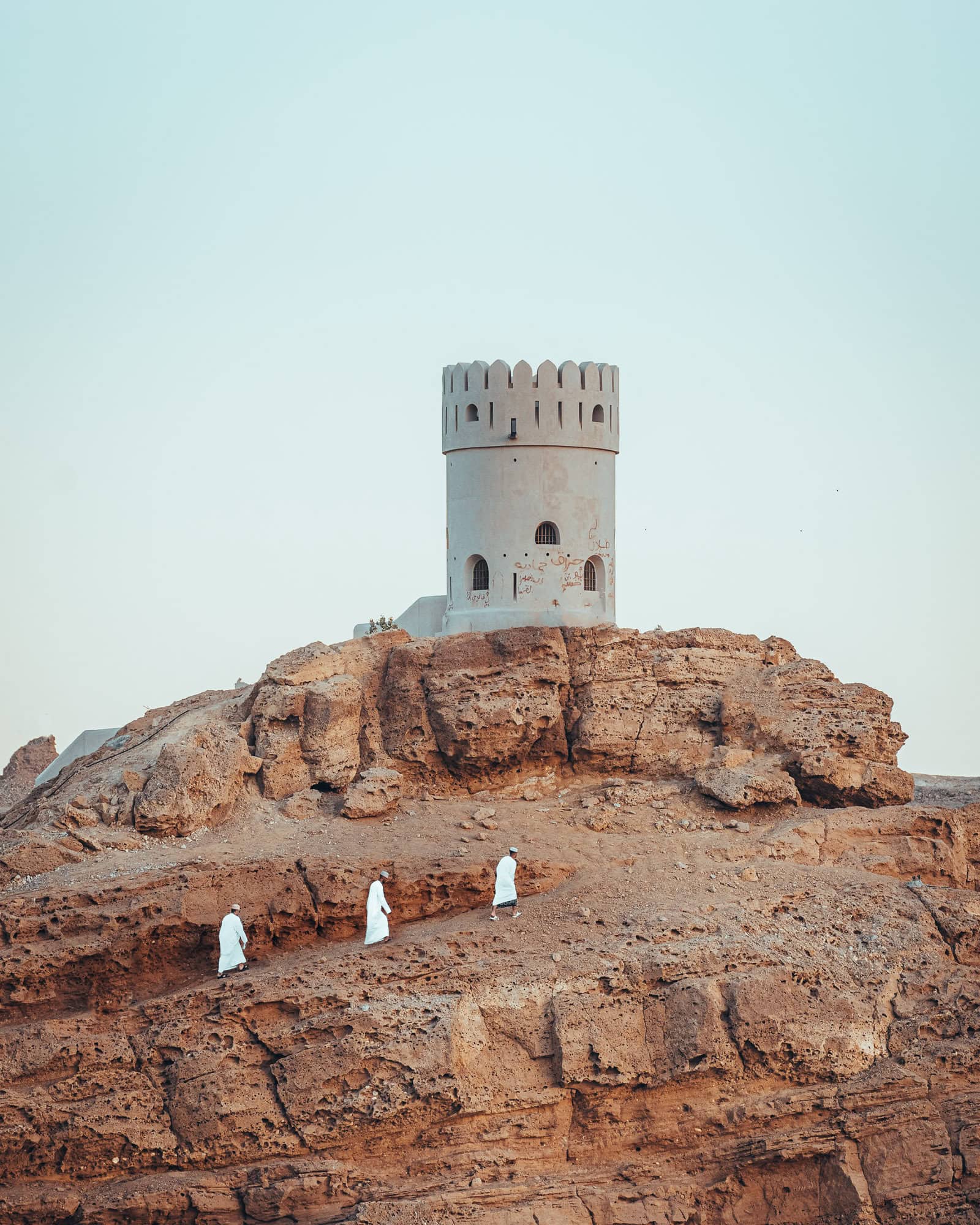 Tower in Oman with Arab men walking to the top