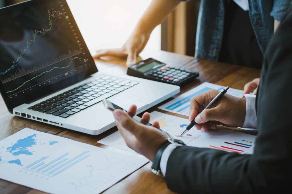 Business professionals analyzing financial data on a laptop and documents.