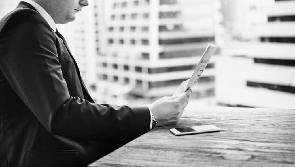 Business professional reviewing financial documents outdoors in city setting.