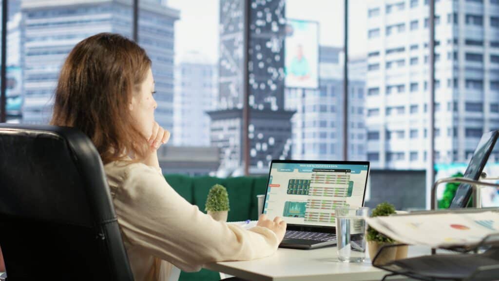 Businesswoman working on financial spreadsheets at office with city view.