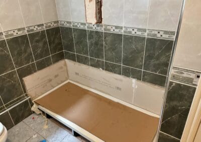 Unfinished bathroom with tiled walls and cardboard covering.