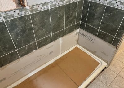 Partially installed shower with green tiles.