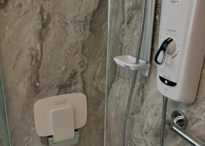 Modern shower with marble wall and safety bar.