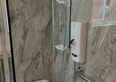 Modern shower with adjustable handheld nozzle and marble tiles.