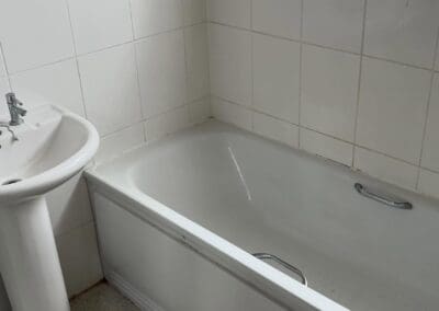 White bathtub and sink in tiled bathroom.