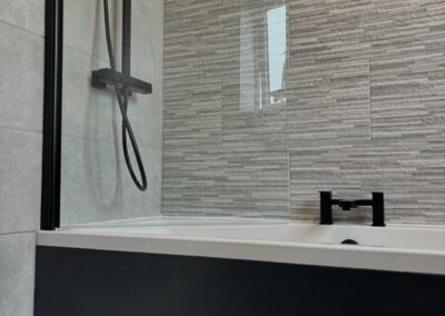 Modern bathroom with tiled bathtub and shower fixture.
