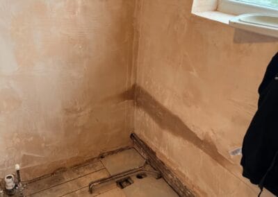 Bathroom under renovation, plumbing exposed.