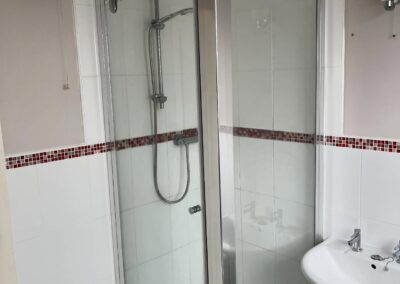 Small bathroom with glass shower and sink.