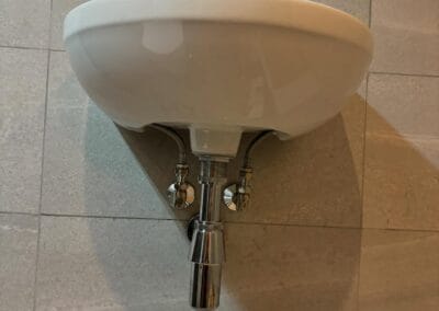 Wall-mounted bathroom sink with faucet and drain pipes.