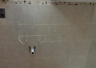 Bathroom under construction with beige tiles and plumbing.