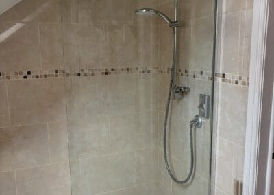 Modern tiled shower stall with glass door.
