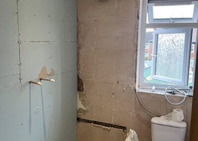 Bathroom under renovation, exposed walls and pipes.