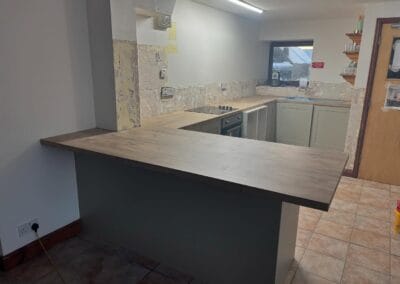 Unfinished kitchen with wooden countertops and tiled floor.