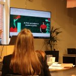 A photo from the PILS Toolkit launch, showing lots of audience members looking at a screen with the words 'PILS believe in accces to jsutice' written on it.