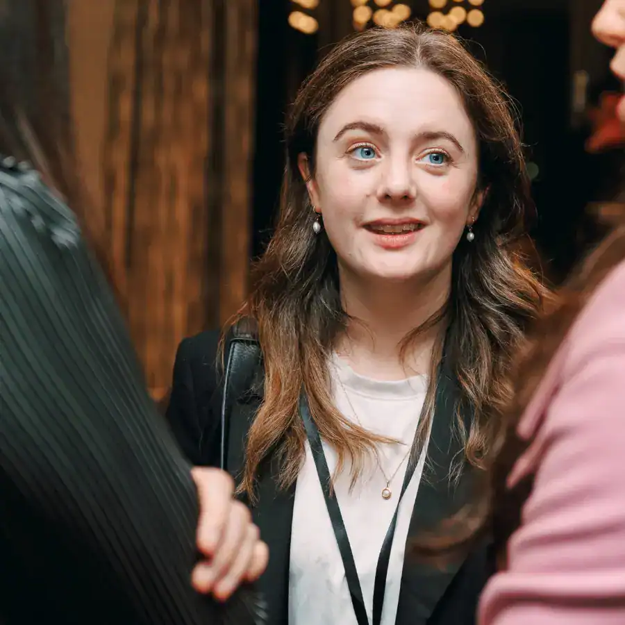 Una Boyd is talking to people who can't be seen, off-camera. She is a white woman with shoulder-length, auburn hair.