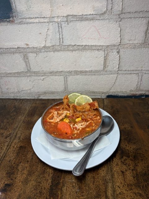 Delicious chicken tortilla soup served in a bowl with lime wedge and crispy tortilla strips. Perfect.