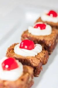 Chocolate brownies topped with whipped cream and cherries from Black Forest dessert.