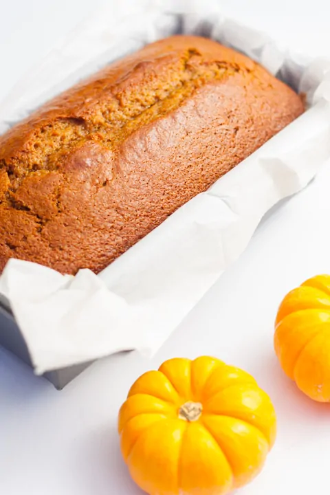 Pumpkin bread with maple glaze and mini pumpkins for fall decor.