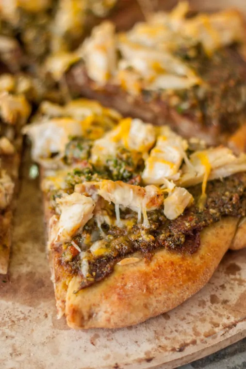 Close-up of Mexican pizza topped with chicken, avocado pesto, and cheese.