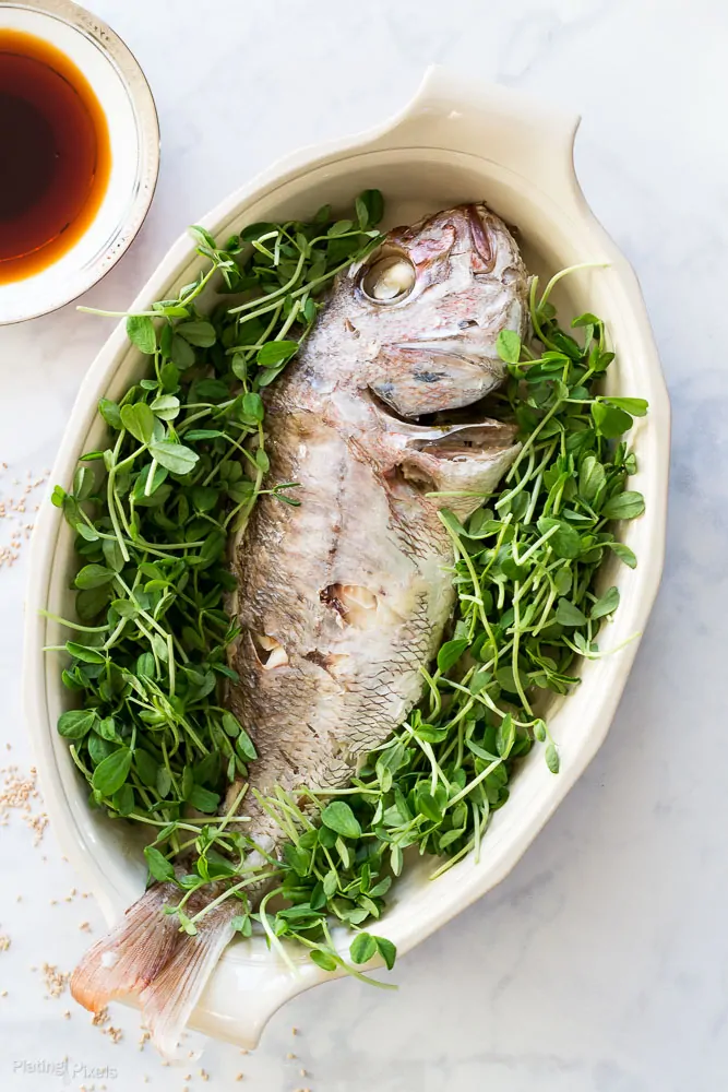 Whole steamed fish garnished with microgreens for Soy Sauce Glazed Fish.